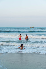 A beach in Hoi An with tourists, boats and fisherman, Vietnam.