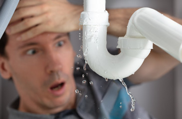 Man Looking At Sink Pipe Leakage In Kitchen