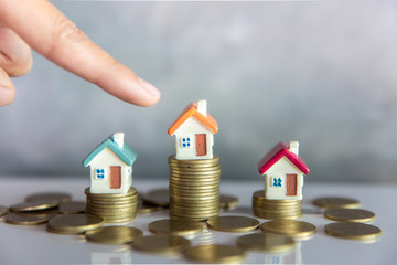 Mini house standing on a heap of coins. The concept of purchase of habitation.