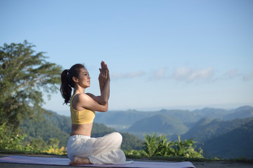 Side view of women practicing yoga. sitting in eagle pose. Anusara Yoga. .beautiful landscape on morning with mist on mountain peaks on natural view, .concept for exercising, health care