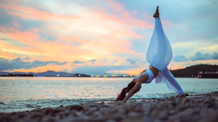 Side view of young women practicing yoga. Three legged dog pose on the beach at morning..landscape view sky on morning outdoor near sea, concept for exercising, healthcare. copy space for text