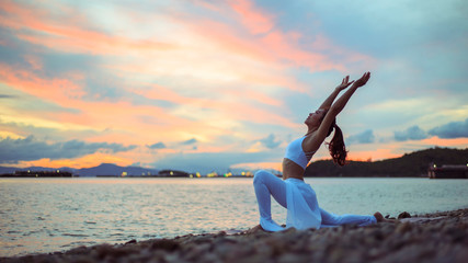 Young woman doing yoga exercise yoga master pose. Amazing yoga landscape in beautiful sky and...