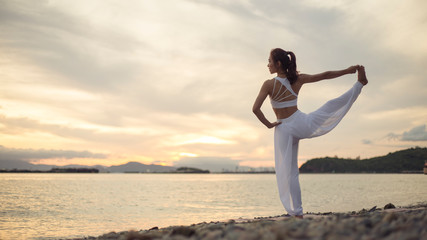 Fototapeta na wymiar Side view of healthy women practicing yoga. standing near sea. exercise Extended Hand to big toe Pose.Utthita Hasta Padangustasana. .beautiful landscape view sky on morning
