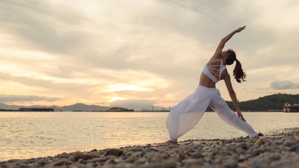 Rear view of woman doing exercise yoga. standing in Warrior lI pose. Amazing yoga landscape in...