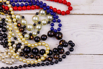Different beads necklaces on white wooden background