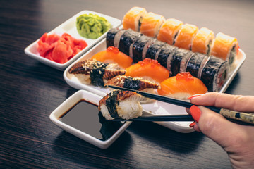 sushi with eel dipped in soy sauce