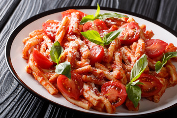 Casarecce pasta with spicy tomato sauce, parmesan and basil with the addition of fresh tomatoes. horizontal