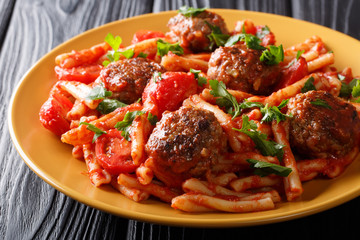 Pasta Casarecce recipe with meat balls, herbs and cheese in tomato sauce closeup on a plate. horizontal