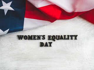 Fototapeta na wymiar Beautiful card for Women's Equality Day. Wooden letters with a congratulatory inscription on a white background. Close-up, top view. Congratulations for loved ones, relatives, friends and colleagues