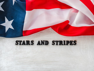 Happy American Flag day. Wooden letters with a congratulatory inscription on the background of wooden boards. Close-up, top view. Preparation for the holiday. Congratulations for friends, colleagues