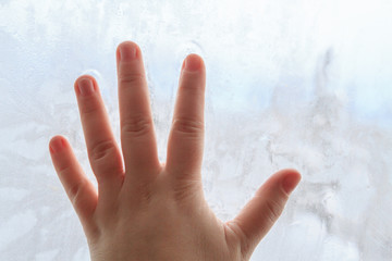 Hand on frozen winter cold window with patterns