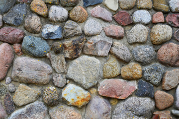 Wall of stones of different shape, size and colors as abstract textured background.