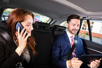 Businesswoman Sitting Inside Car Beside Her Male Colleague