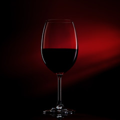 Silhouette of glass of red wine on black to red gradient background. Close-up studio shot.