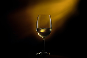 Conceptual shot of glass with white glass on a dark gradient black to yellow background.