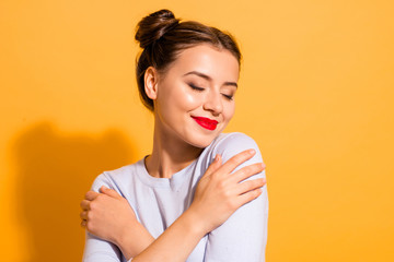 Close-up portrait of her she nice attractive lovely peaceful sweet winsome fascinating cheerful girl hugging herself feelings isolated over bright vivid shine yellow background