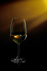 Glass of white wine on black to yellow background. Concept studio shot.