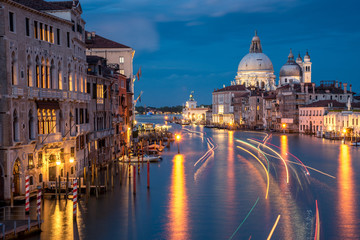 Beautiful landscape sunset view of traditional Gondolas on famous Canal Grande with historic Basilica di Santa Maria della Salute in the background in romantic golden evening light at sunset in Venice