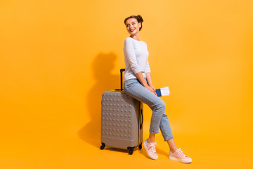 Profile side full length body size photo of cute charming youngster in light denim clothes standing in queue for her jet sitting on trolley bag holding documents on vivid background