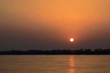 Naklejka na ściany i meble Sunset low sun in orange sky at river Assam in India