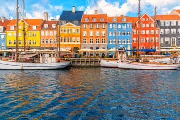 Nyhavn area of popular bar and restaurant at beautiful blue sky, with colorful facades of old houses and old ships in the Old Town of Copenhagen, capital of Denmark.