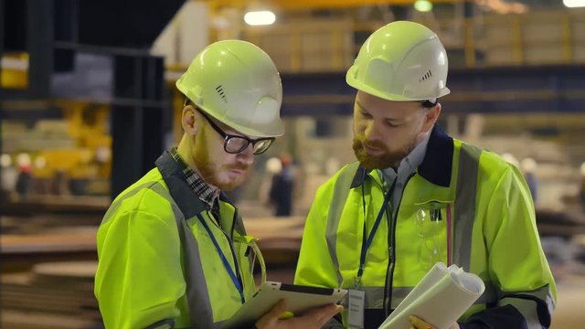 Factory workers in a hard hat using a tablet computer