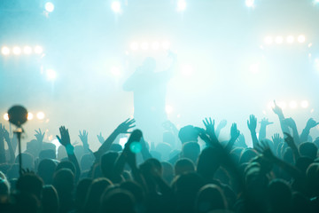 concert, silhouettes of happy people raising up hands, Music show. Bright scene lighting in club....