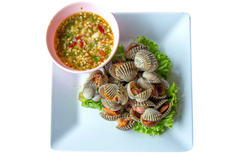 Scalded fresh cockles and on white plate decorated with lettuce, focus selective