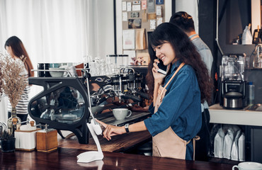Asian Barista use tablet take order from customer in coffee shop,cafe owner writing drink order at counter bar,Food and drink business concept,Service mind concept.restaurant waiter worker