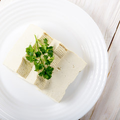 Flat lay view at Soy Bean curd tofu on clay dish closeup. Non-dairy alternative substitute for cheese