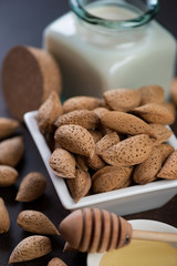 Close-up of unpeeled almond nuts with almond milk in the background, selective focus