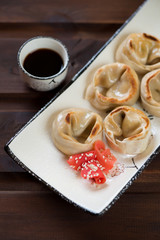 Close-up of pan fried asian dumplings with salmon stuffing, studio shot on a dark brown wooden background