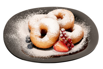 Juicy fresh doughnuts covered with powdered sugar on black plate on white isolated background