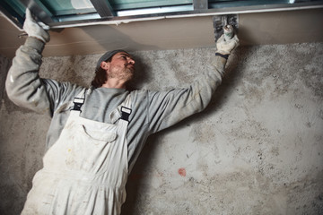 Worksman plastering gypsum walls inside the house.