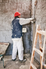 Real construction worker making a wall inside the new house.
