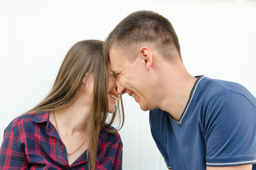 guy with short haircut and girl with long hair and freckles smiling touch their heads