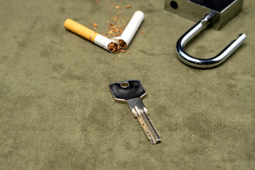 Exemption from bad habits. The key on the background of a broken cigarette and an open lock