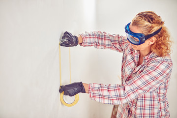 Working woman plastering / painting walls inside the house.