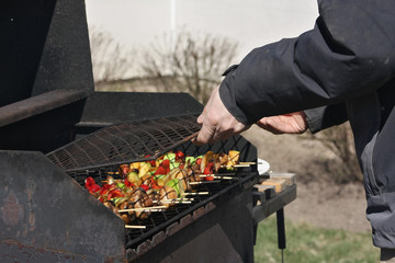 A man preparing vegetables on a grill in summer. Close up.