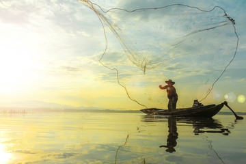 Silhouette of fishermen using coop-like trap catching fish in lake with beautiful scenery of nature morning sunrise. Beautiful scenery at Bang-Pra, Chonburi Province Thailand.