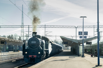 Fototapeta na wymiar Kouvola, Finland - April 18, 2019: Old steam train Ukko-Pekka is leaving the station at morning.