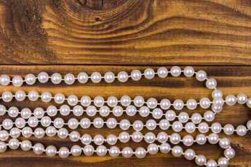 Pearl necklace on wooden background. Top view, copy space