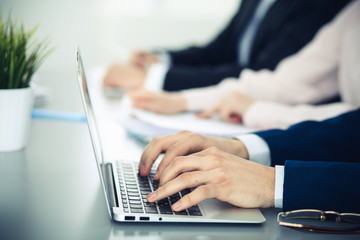 Group of business people working together in office. Man hands typing on laptop computer
