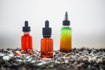 Vape concept. Beautiful colorful vape liquid glass bottles outdoor on stones. Useful as background...