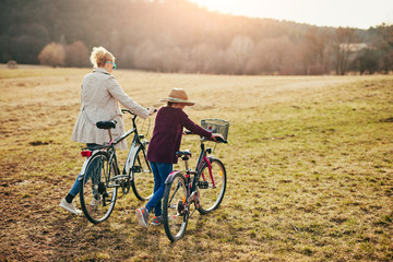 Fototapeta premium Mother and daughter with bicycles on countryside.