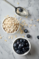 A fresh blueberries and Organic rolled oats in bowl, on marble background. Concept of cooking ingredients, decorate bakery, healthy eating and nutrition.