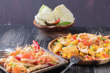 corn and papaya salad on wooden plate Thai style