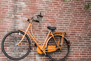 Fototapeta na wymiar bike in Dutch national color orange, against brick wall background