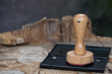 close up vintage wooden stamp and black ink pad on wooden desk, against black background