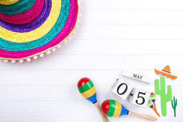 Mexican hat with maracas, cube calendar and paper cactuses on wooden table